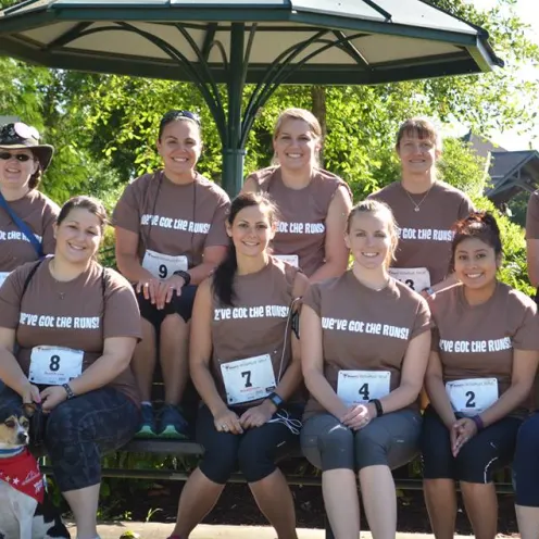 Staff photo at a running event and everyone is wearing matching brown shirts